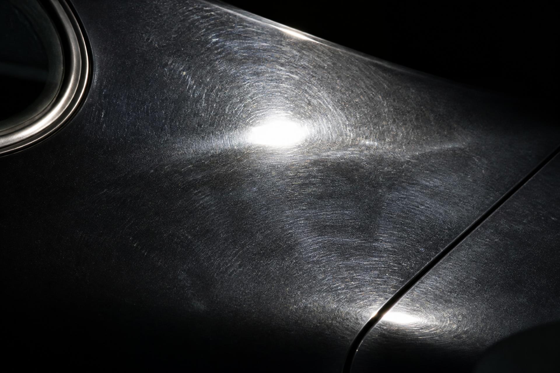 Oxidized, swirl-marked black car panel before correction